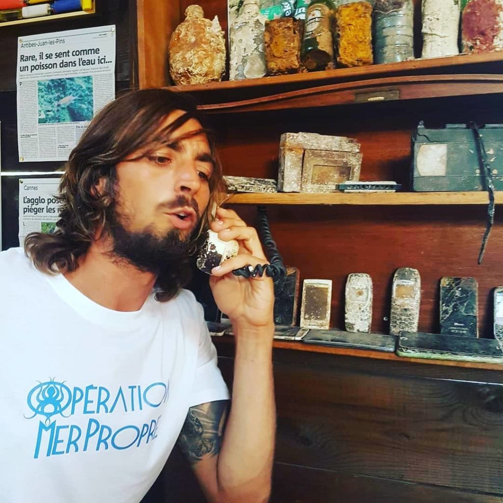 Guillaume au téléphone (de récupération) dans le musée des objets récupérés par Opération Mer Propre